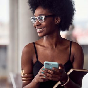 Cheerful african american woman holding smartphone and notepad